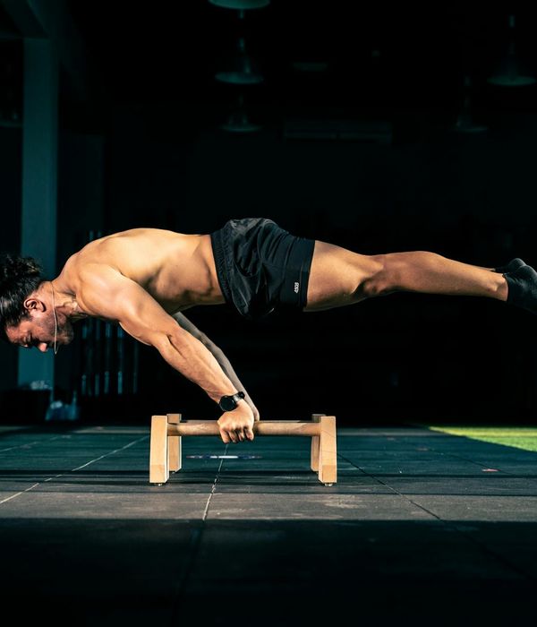 Man performing a controlled bodyweight exercise in a dark, focused environment.